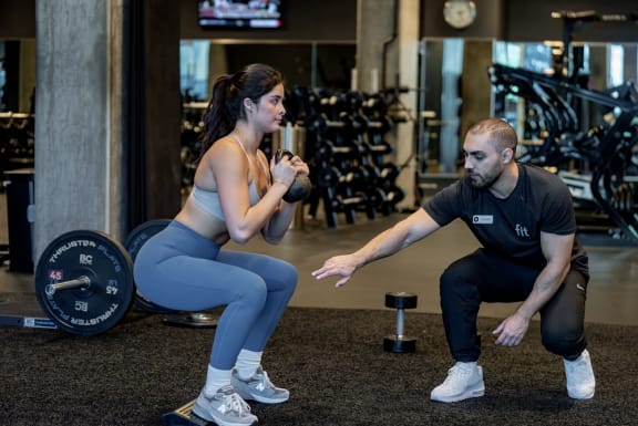 a man and a woman doing squats in a gym with weights
