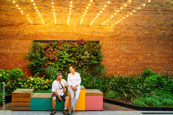 Two people sitting on a bench under a string of lights.