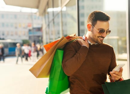 a man with shopping bags looking at his cell phone