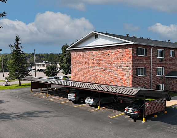 A parking lot with cars parked in front of a red brick building.