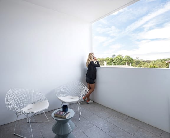 a woman standing on a balcony talking on her cell phone