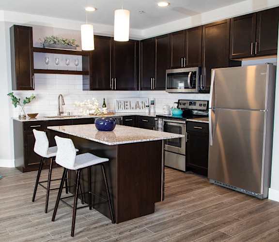 A kitchen with a white counter top and a stainless steel refrigerator.