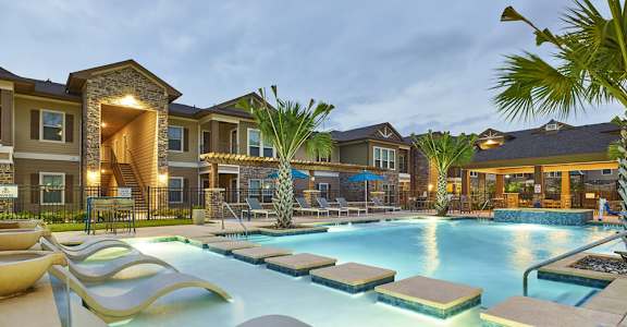A large outdoor swimming pool with a slide and loungers.
