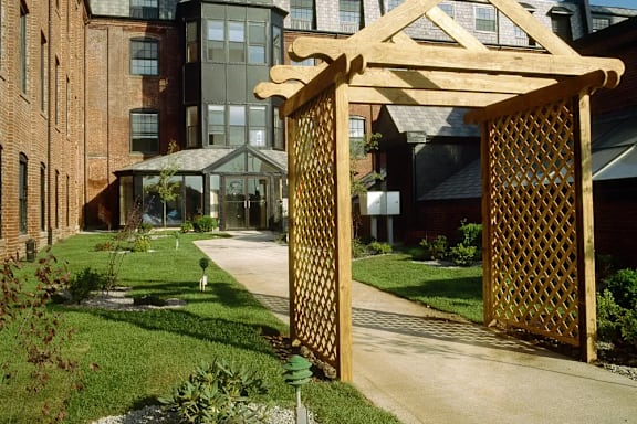 A wooden gate with lattice work leads to a building.