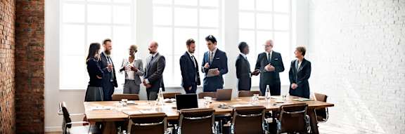 A group of business people are gathered in a meeting room.