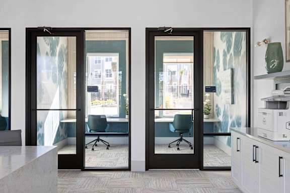 A modern office with glass doors leading to a balcony.  at The Quinn Luxury Apartments, Pensacola, FL