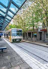 A yellow tram is on a street with a blue pole.