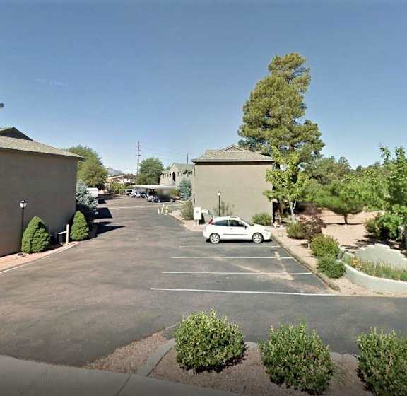 A parking lot with a white car and a building in the background.