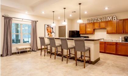 A kitchen with a bar area and chairs. at Arbours at Satsuma Apartments, Mobile, AL, 36572