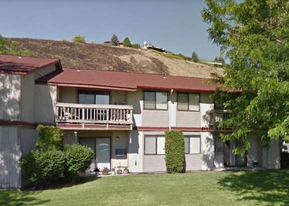 an apartment building with a hill in the background