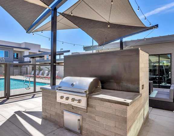 A modern outdoor kitchen with a grill and an umbrella.