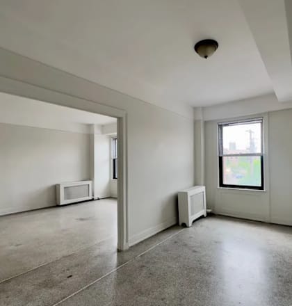 an empty room with a window and a radiator