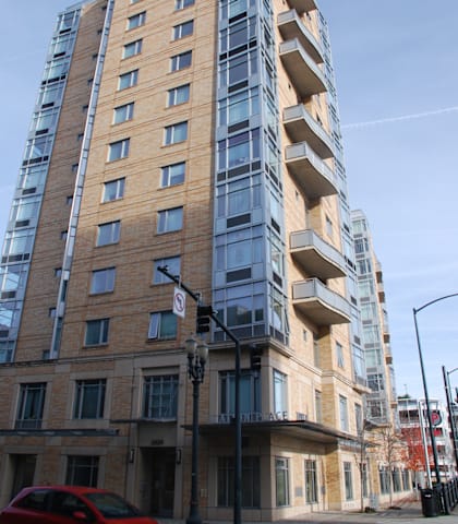 A red car is parked on the street in front of a building.