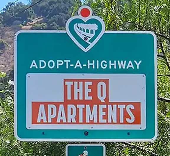 A sign for Adopt-A-Highway is displayed in front of a mountain.