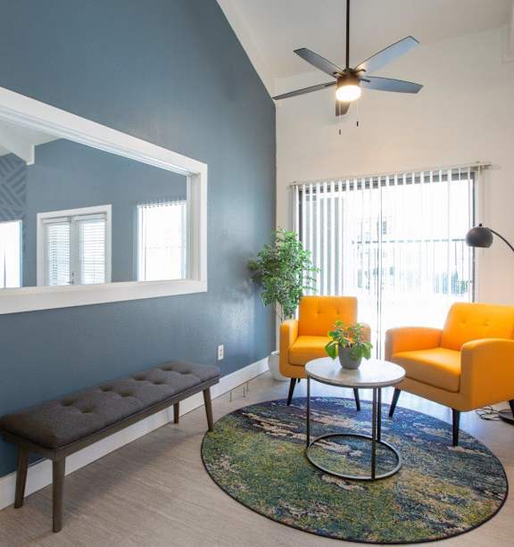 A living room with a blue wall and a ceiling fan.