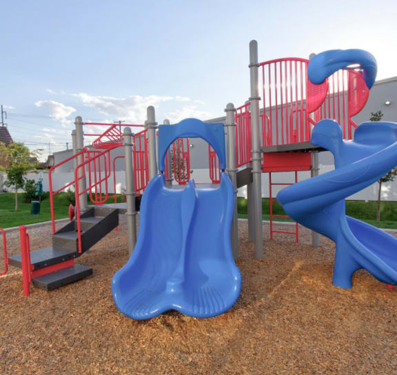 a playground with a blue slide and red hardware at Calla Homes in Milcreek, UT