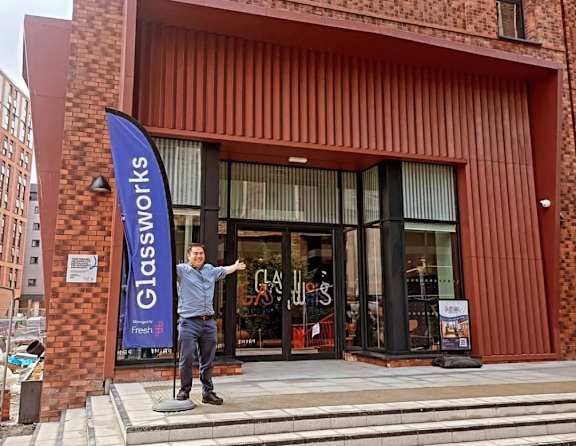 A man stands in front of a Glassworks store.