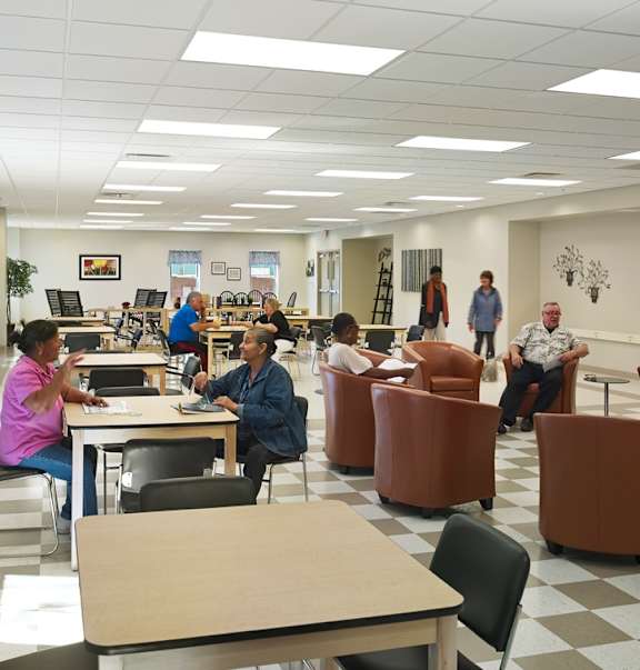 people sitting at tables and chairs in a library