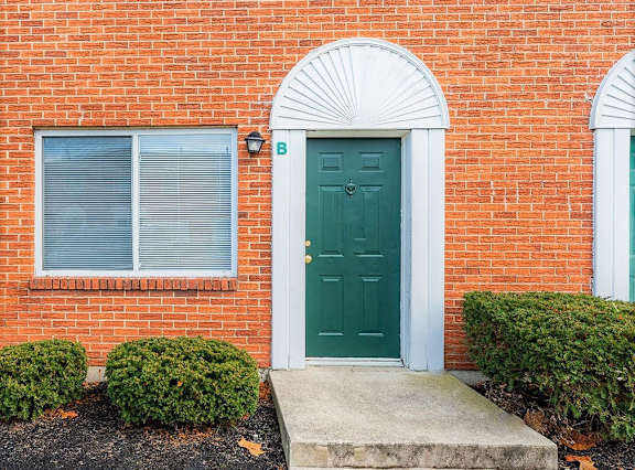 A family of four hugging outside a house.