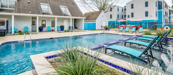 a swimming pool with lounge chairs and a house in the background
