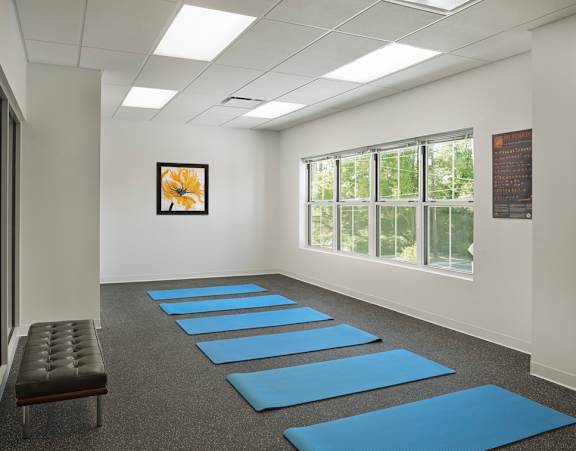 a yoga room with blue yoga mats on the floor and a bench