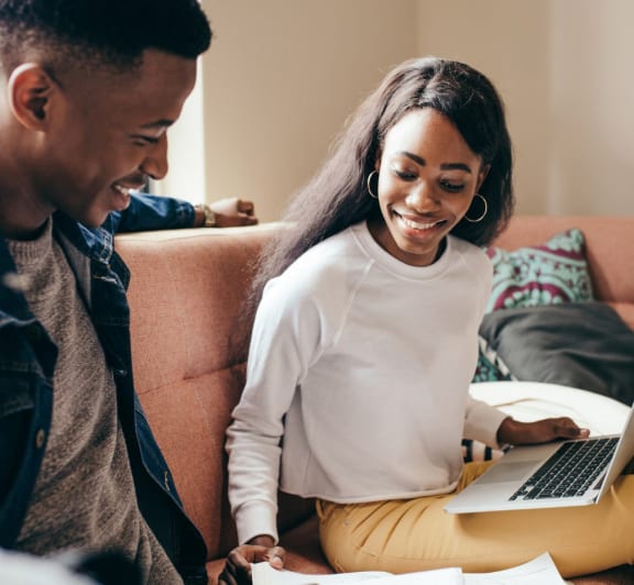 a couple sitting on a couch looking at a laptop