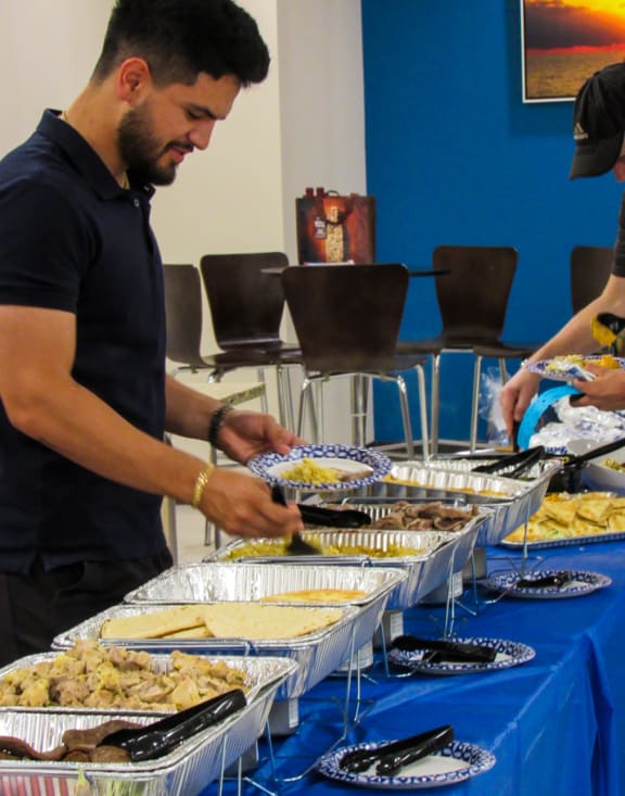 people picking up food from a buffet table