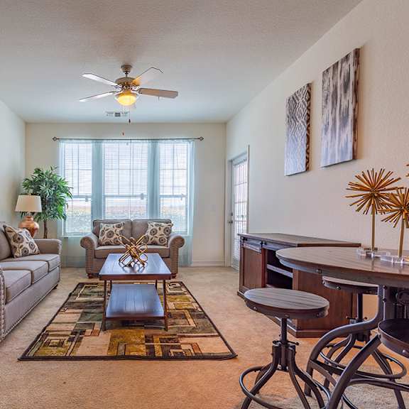 A living room with a grey couch, a coffee table, and a ceiling fan.