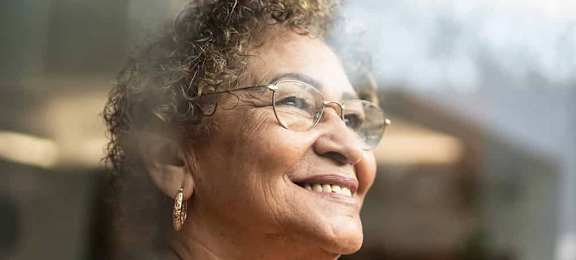 a woman wearing glasses and a red and black shirt smiles