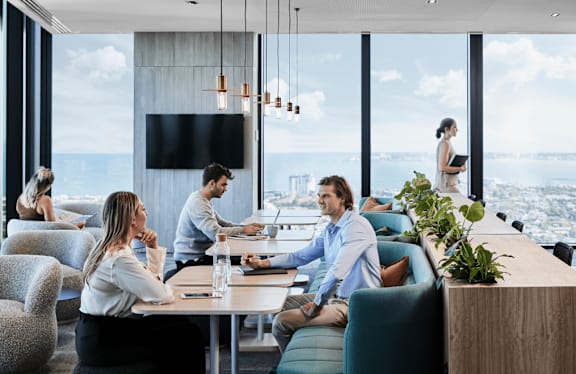 A group of people are sitting around a table in a modern room with a view of the city.