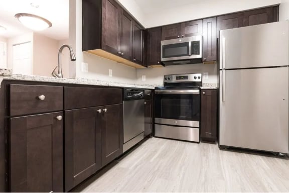 a kitchen with stainless steel appliances and wood cabinets at Elme Manassas in Manassas, VA