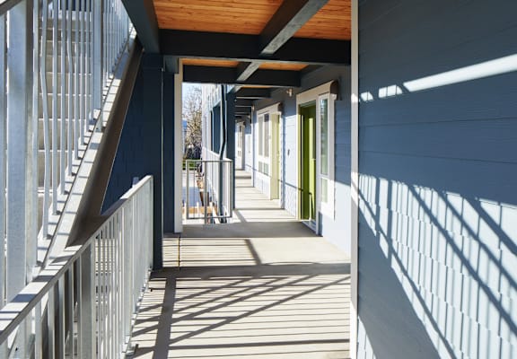 A long hallway with a metal railing on the left and a wooden ceiling.