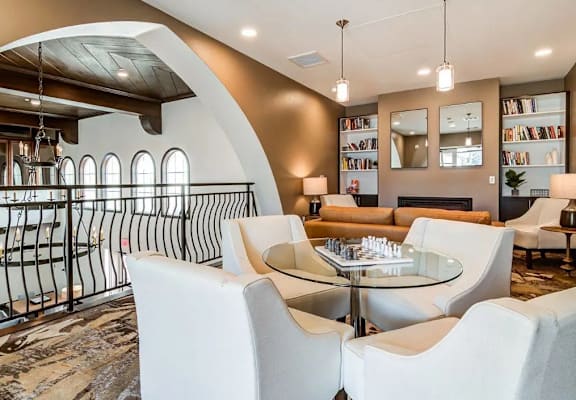 A modern living room with a glass table surrounded by white chairs.