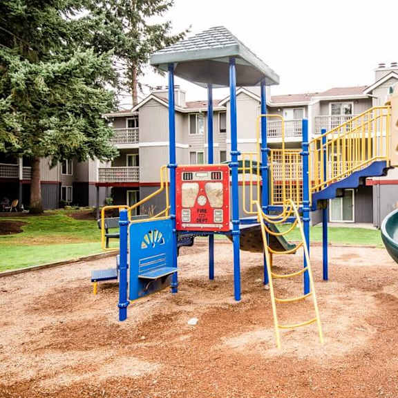 A playground with a green slide and a blue and yellow play structure.