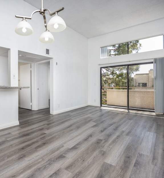 an empty living room with a kitchen and a sliding glass door