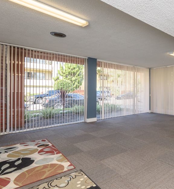 an empty room with large windows and a rug on the floor