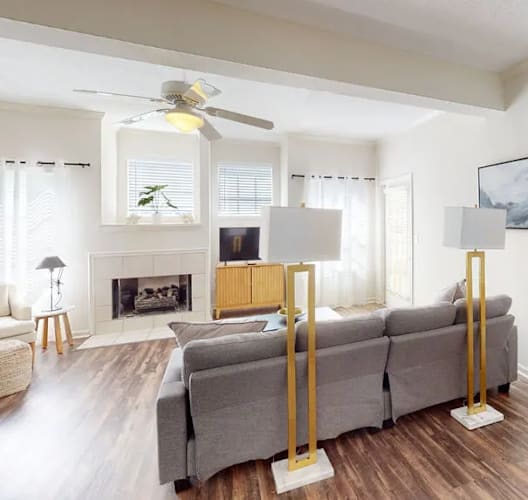 A living room with a grey couch, a fireplace, and a painting on the wall.