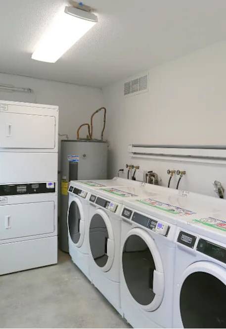 A laundry room with a row of washers and dryers at Tigardville Apartments, Tigard, OR 97223