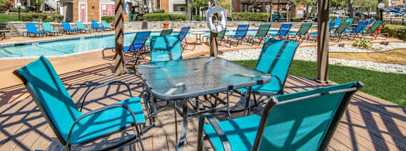 a patio with chairs and tables and a pool at Foxborough Apartments, Irving, TX