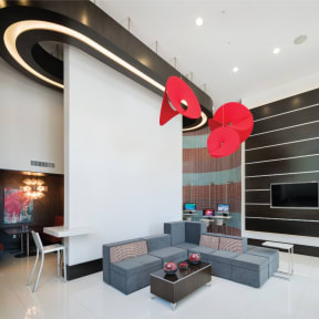a rendering of a lobby with a gray couch and a red flower chandelier