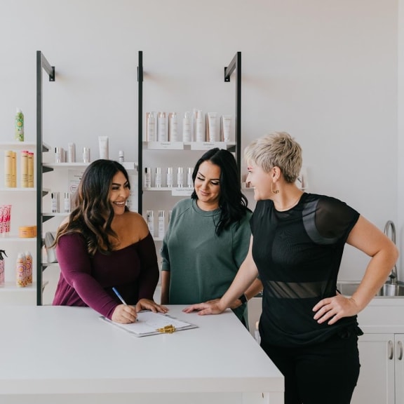 three women standing around a counter in a beauty store at Versus, Calgary, Alberta