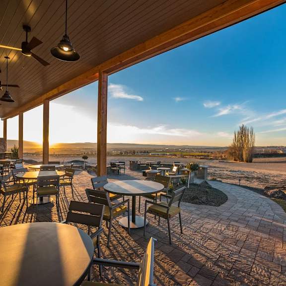 A patio with tables and chairs overlooking a field.at Alante Homes at Spring Run, Caldwell Idaho