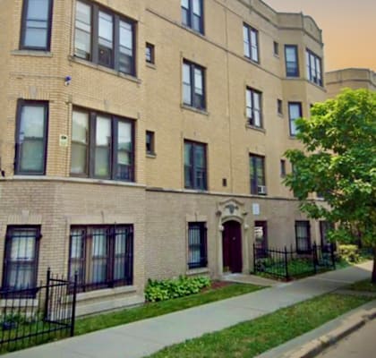 a brick apartment building with a tree in front of it