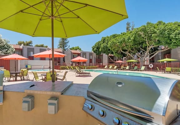 A yellow umbrella is in the foreground of a sunny outdoor area. at Spring Meadow Apartments, Glendale, AZ, 85302
