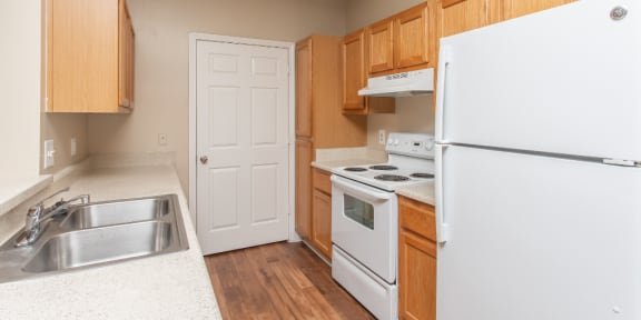 an empty kitchen with white appliances and wooden cabinets