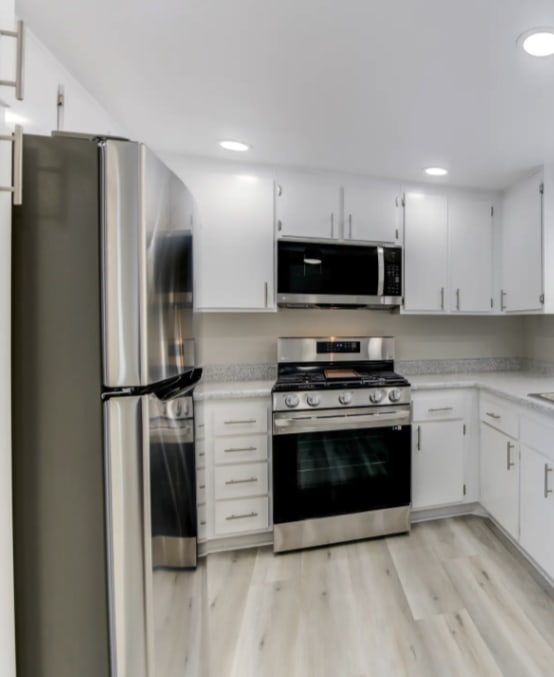 a kitchen with white cabinets and stainless steel appliances