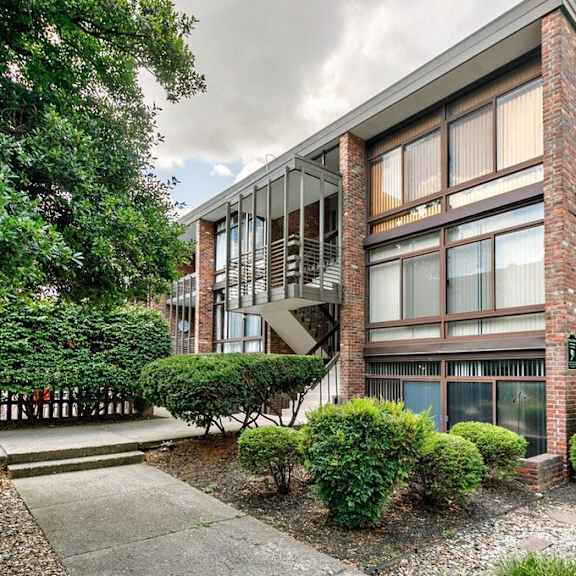 the exterior of a brick apartment building with trees and a sidewalk