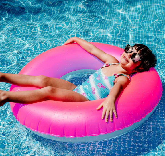 a girl laying on a pink inner tube in a pool  at Signature Pointe Apartment Homes, Athens, 35611