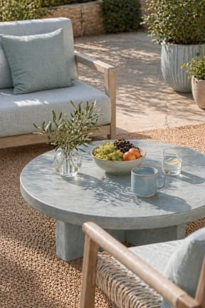 A breakfast table with a plate of fruit and two cups of coffee.