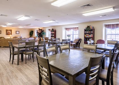 a dining room with tables and chairs and a living room with a couch